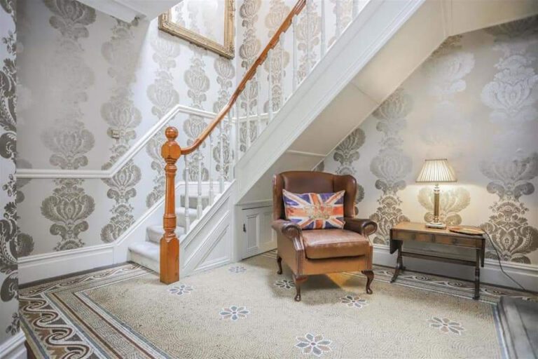 Hallway with damask feature wallpaper and painted staircase
