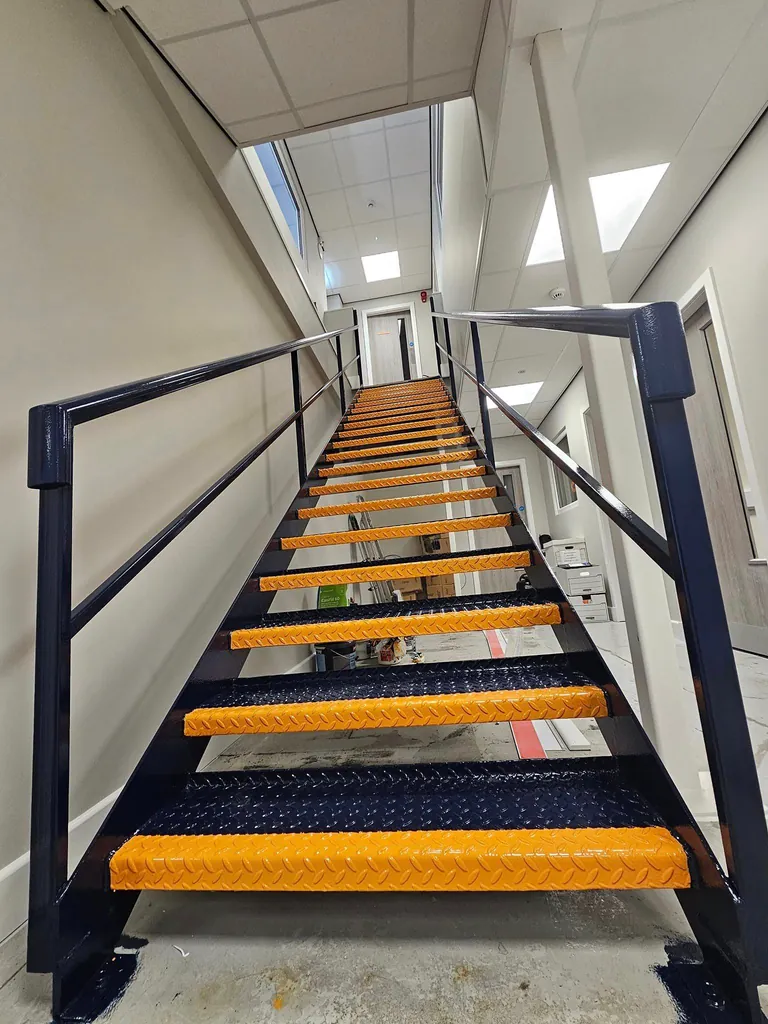 Industrial staircase with yellow treads and dark painted handrails