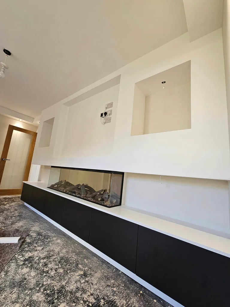 White-painted media wall with recessed shelving and dark cabinets