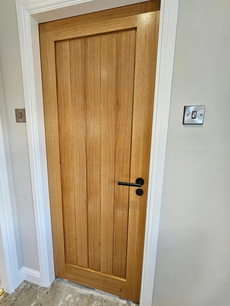 Wooden interior door with a white painted frame and pale grey walls
