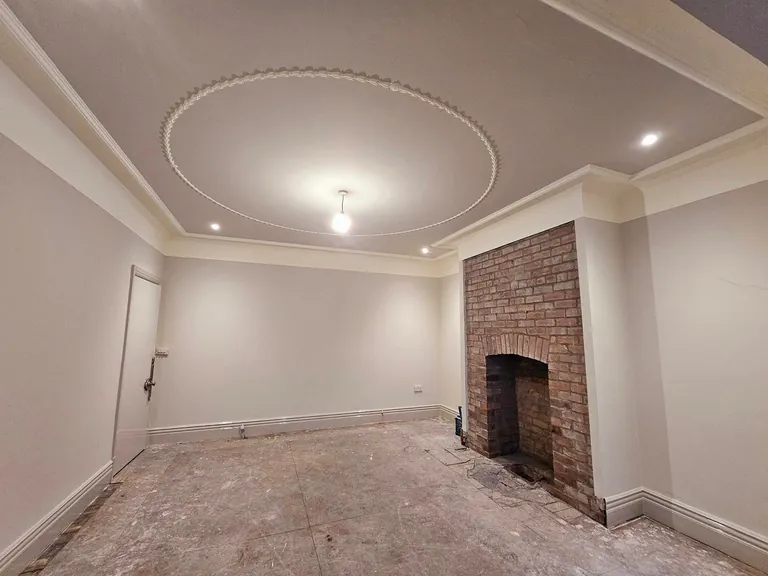 Freshly painted grey room with decorative ceiling moulding and a brick fireplace